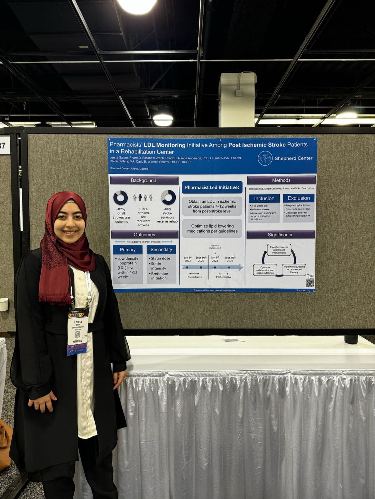 A person wearing a red hijab stands next to a scientific poster titled