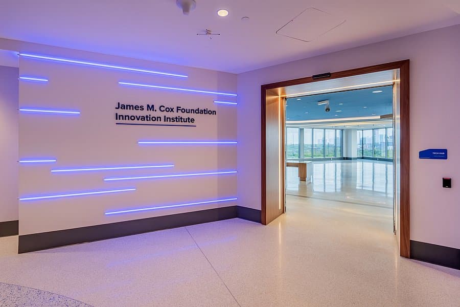 A modern hallway with blue LED light strips on the wall and a sign reading 