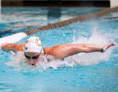 A swimmer in goggles and a swim cap performing the butterfly stroke in a pool.